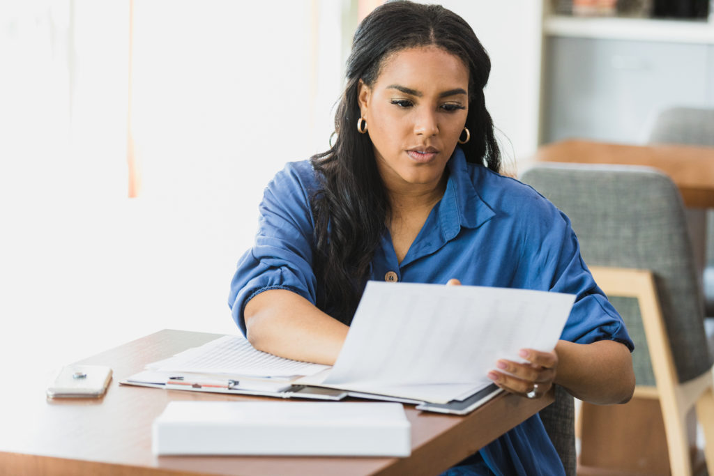 A serious mid adult businesswoman examines a spreadsheet while on a business trip.
