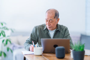 An active senior man is working on a laptop at home.