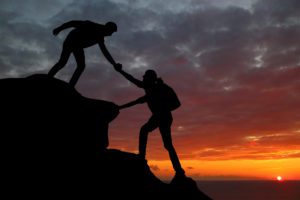 couple hiking up a mountain with one helping the other up