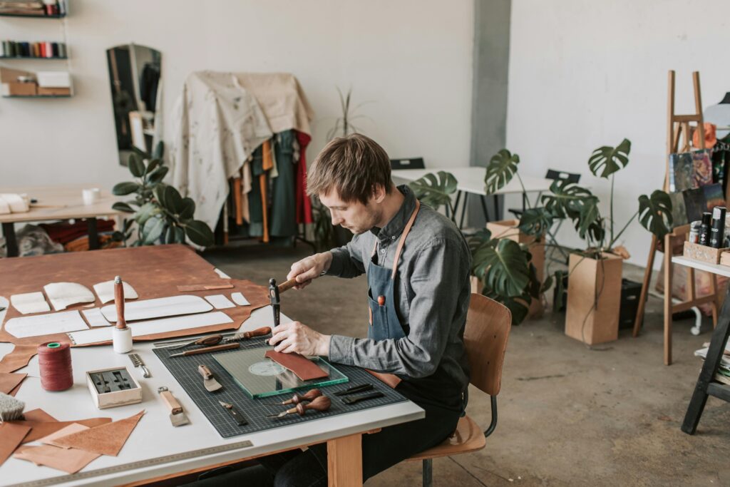 Leather craftsperson working at a table in a stylish workshop.