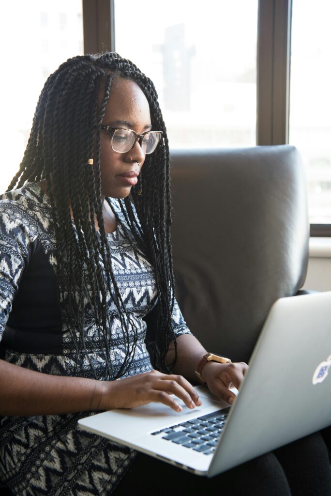 Focused young woman typing on laptop in a contemporary workspace.