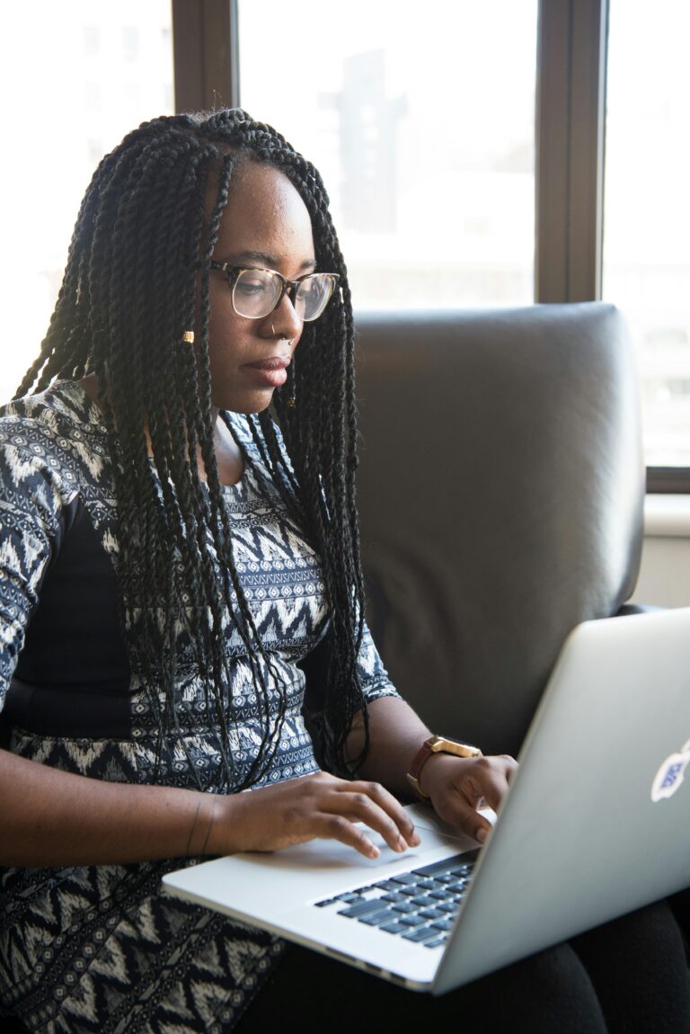 Focused young woman typing on laptop in a contemporary workspace.