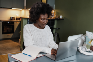 A young woman is at home, she is sitting at the table and working on a laptop