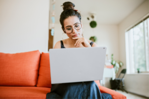 An Indian American woman works on a design project in the comfort of her apartment living room.
