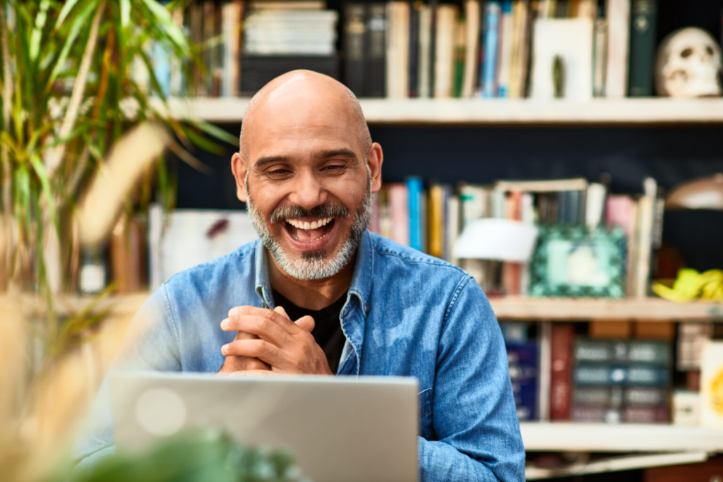 Man laughing and smiling at his computer.