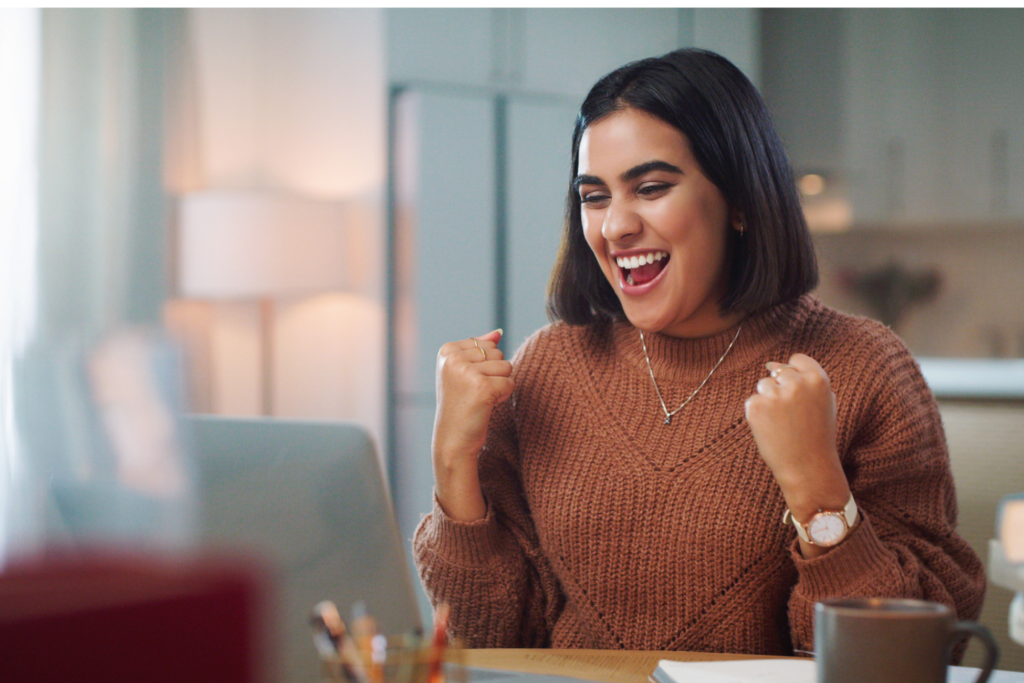 Shot of a young woman cheering while using a laptop to study at home. Just got my results... I passed!