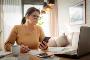 Woman using mobile phone and laptop working from home