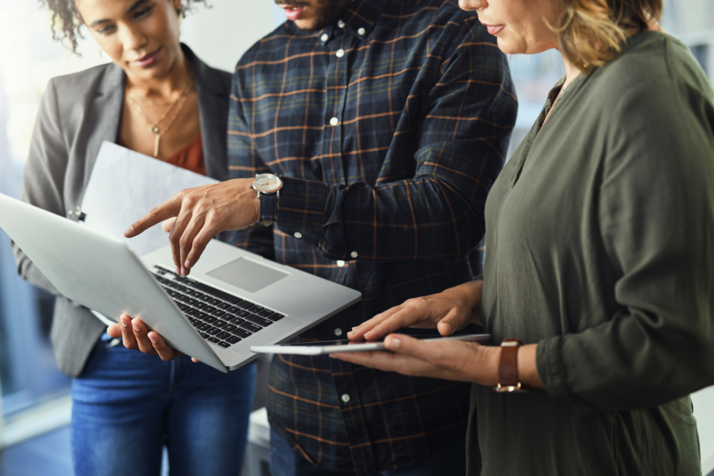 Closeup shot of a group of unrecognisable businesspeople working together on a laptop in an office