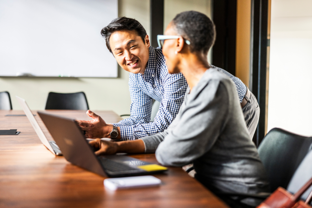 Business colleagues working on laptops in modern conference room