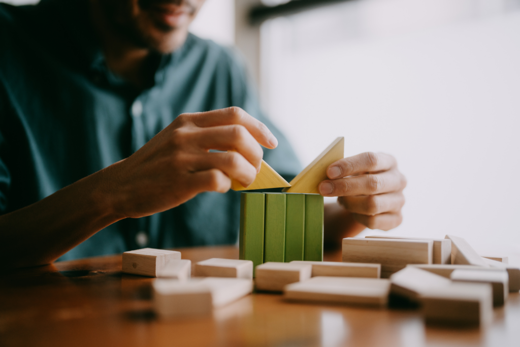 Man playing with green and yellow wooden blocks on table