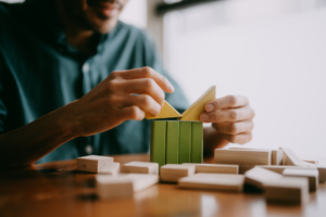 Man playing with green and yellow wooden blocks on table