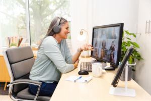 Mid adult woman using computer in home office, video conference with colleagues.