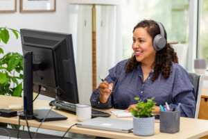 Smiling woman in headphones participates in a video conference at her home office.