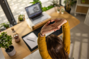 Young businesswoman stretching her arms after working whole day in her home office alone.