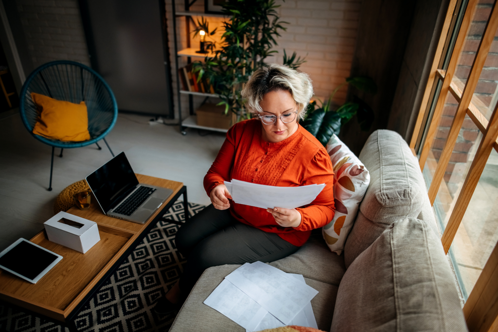 Business woman in her living room on the sofa examines the papers
