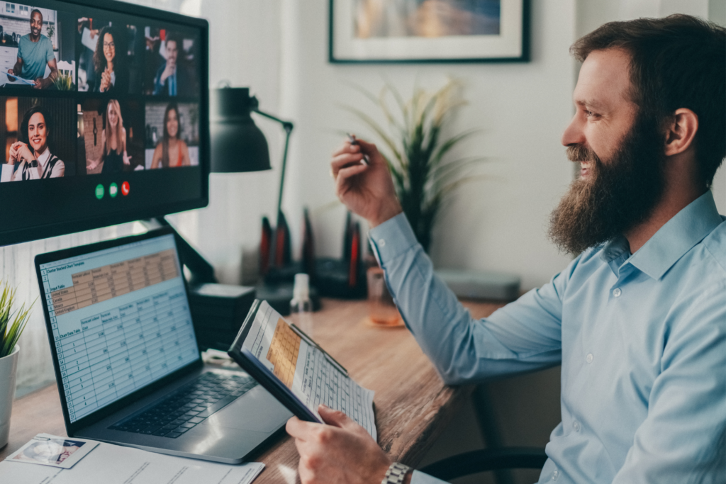 Man with a beard smiles as he has a conversation in an online meeting