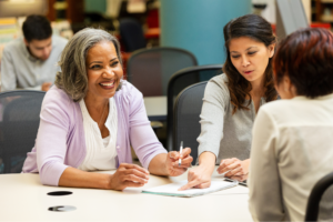Diverse group of women in an indoor setting actively collaborating and engaged in conversation during a meeting.