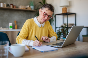 Stylish entrepreneur wearing eyeglasses working on computer at home. Woman analyzing and managing domestic bills and home finance