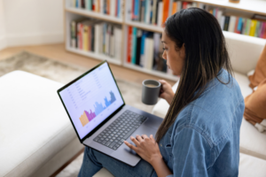African American woman working at home using her laptop while drinking coffee -telecommuting concepts