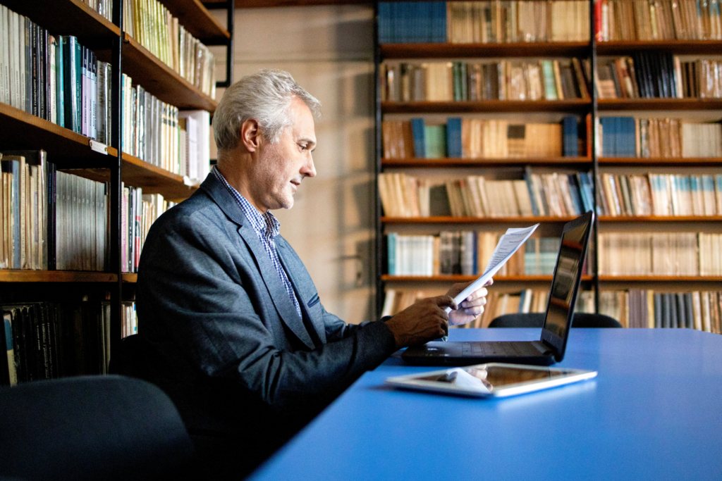 University senior professor in library looks at student statistics stock photo