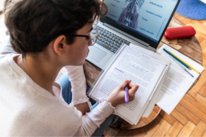 Rear view of a young woman making annotations on her notepad during study at home